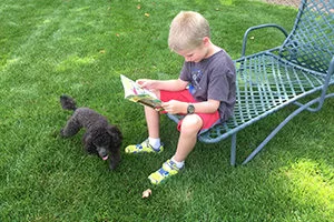 Paula Lillard Preschlack - young boy reading outside.